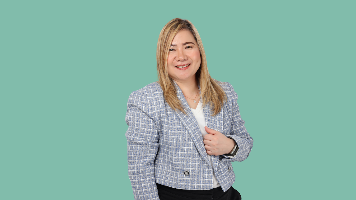 Woman in blazer smiling, teal background.