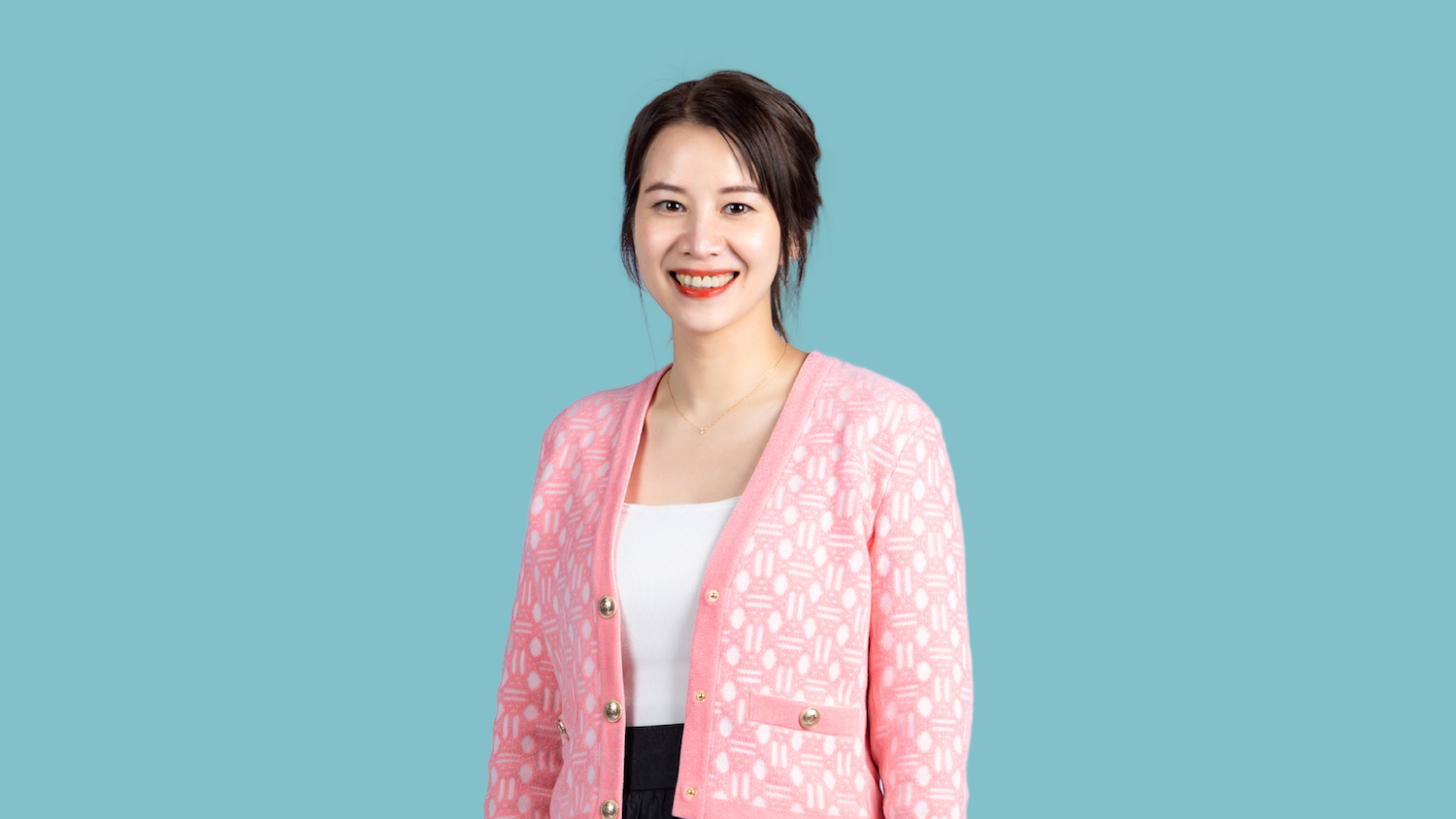 Smiling woman in pink cardigan, blue background.