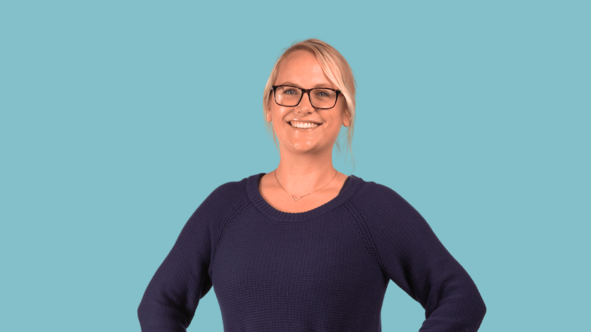 Woman with glasses smiling, wearing a blue sweater.