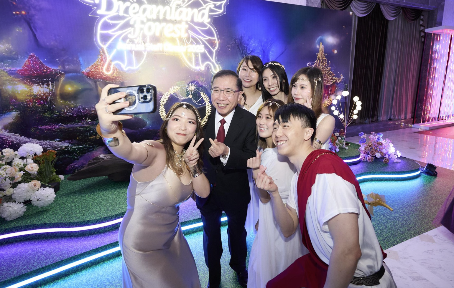 People posing for a selfie at an event with a "Dreamland Forest" backdrop.