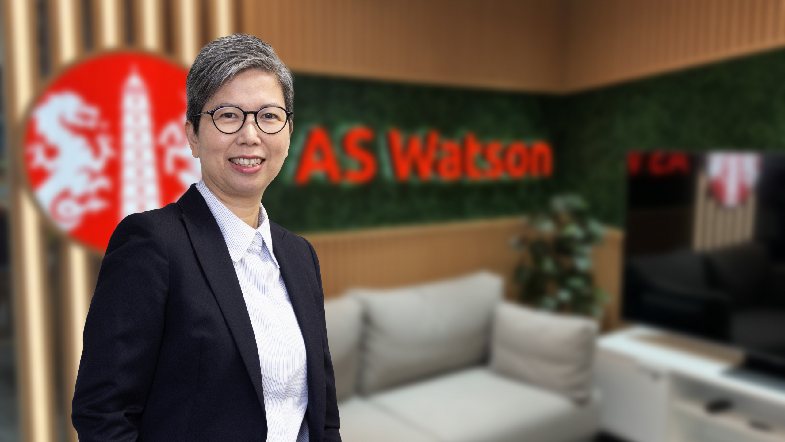 Woman wearing glasses smiling, AS Watson background.