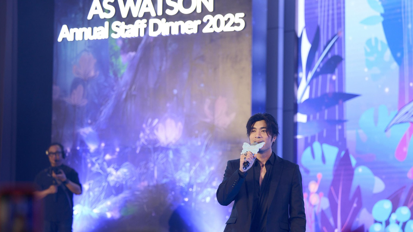 Man speaking at a conference, holding a microphone with a butterfly.
