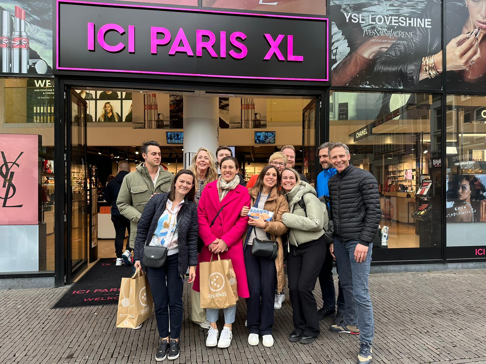 Group of people posing in front of a store with "ICI PARIS XL" sign.