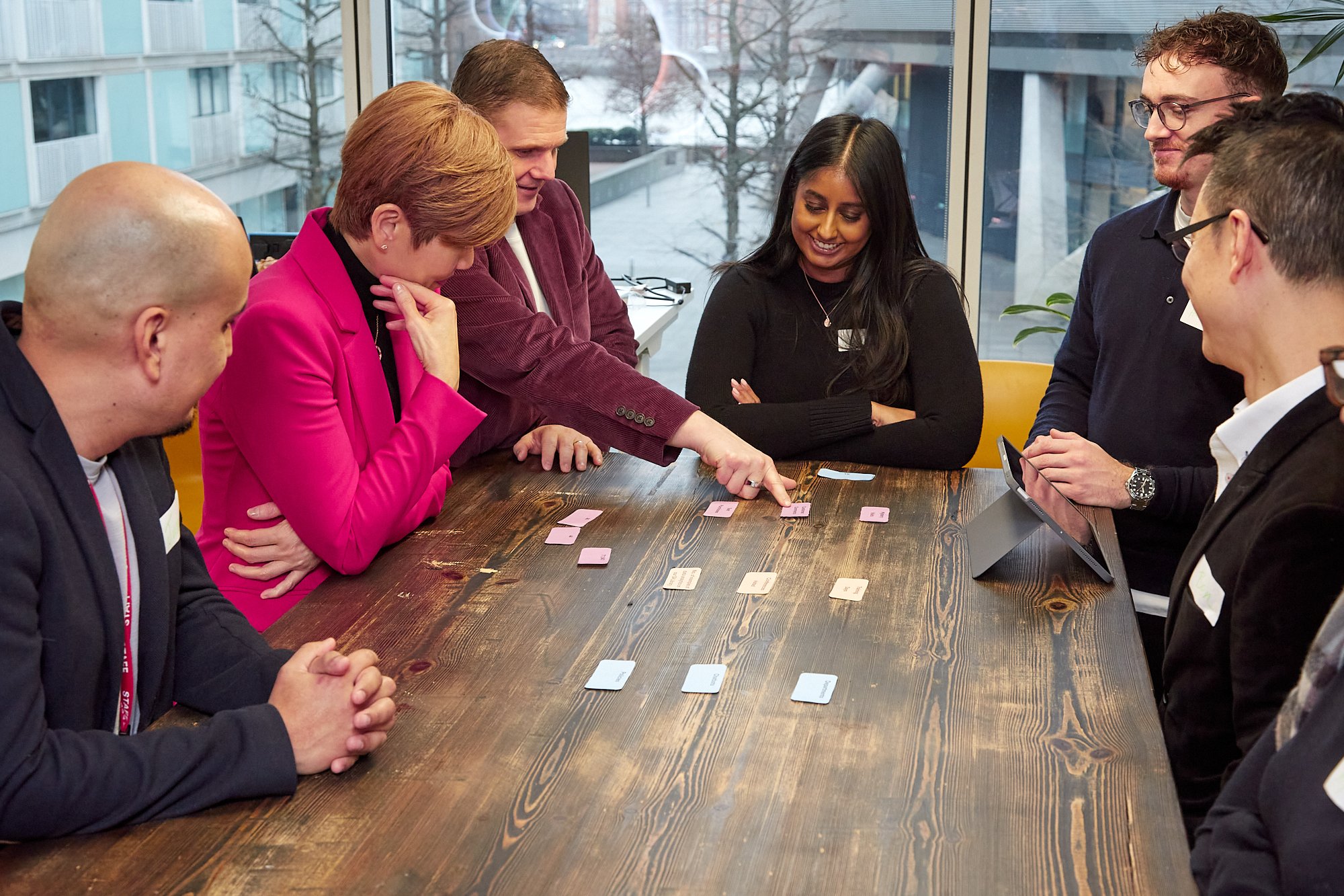 People around a table, discussing cards.