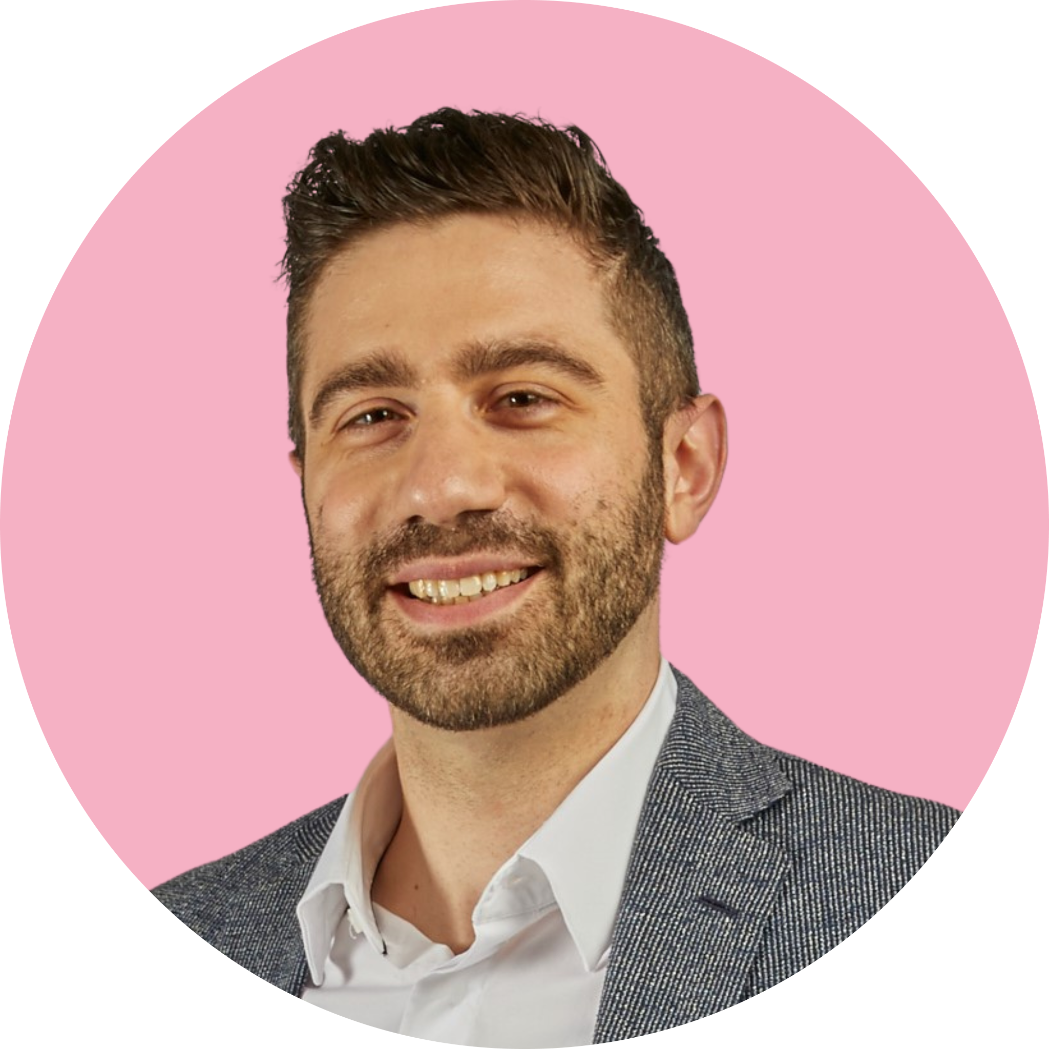 Man in a blazer smiling, pink background.