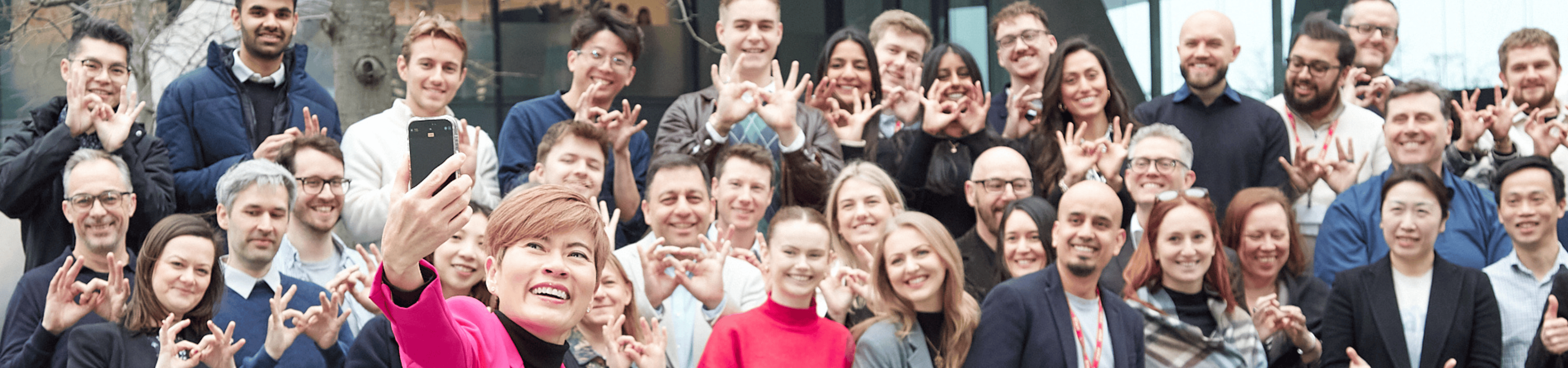 Group of people taking a selfie, making hand gestures.