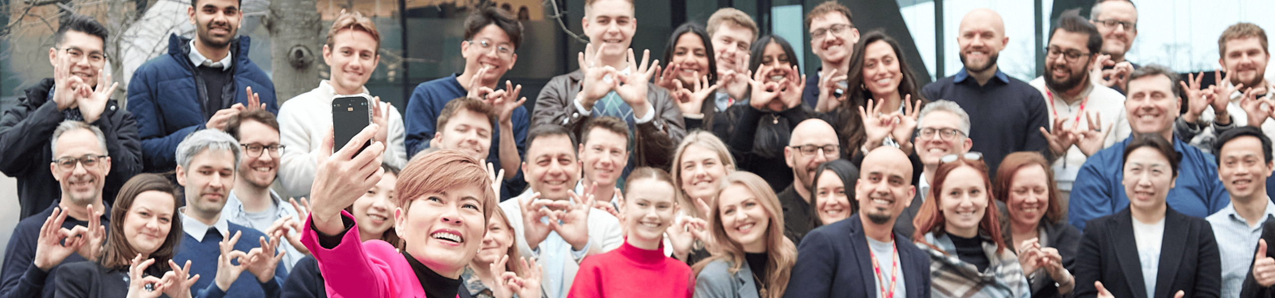 Group of people taking a selfie, making hand gestures.