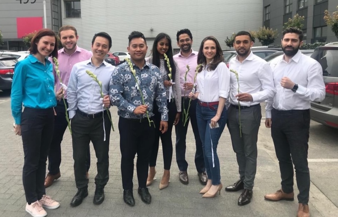 Group of people holding flowers, posing for a photo.