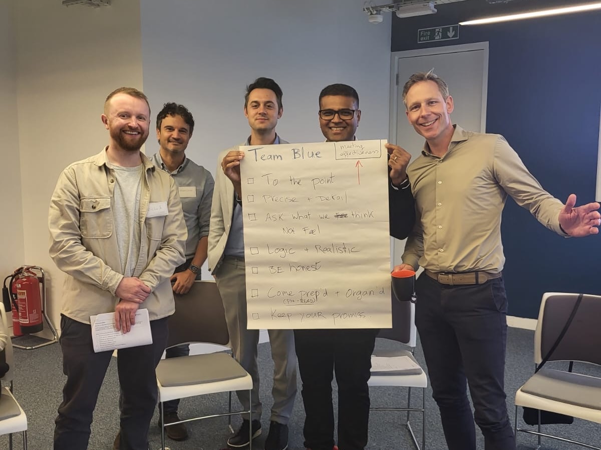 Group of men holding a paper with meeting objectives.
