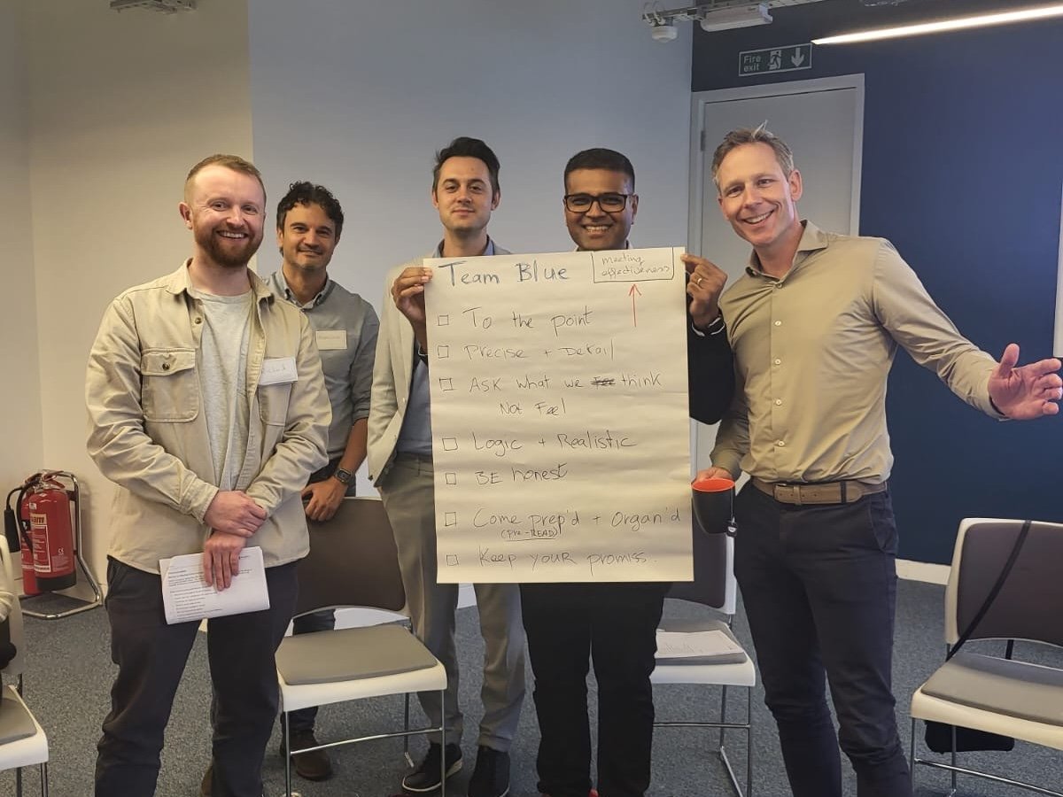 Group of men holding a paper with meeting objectives.