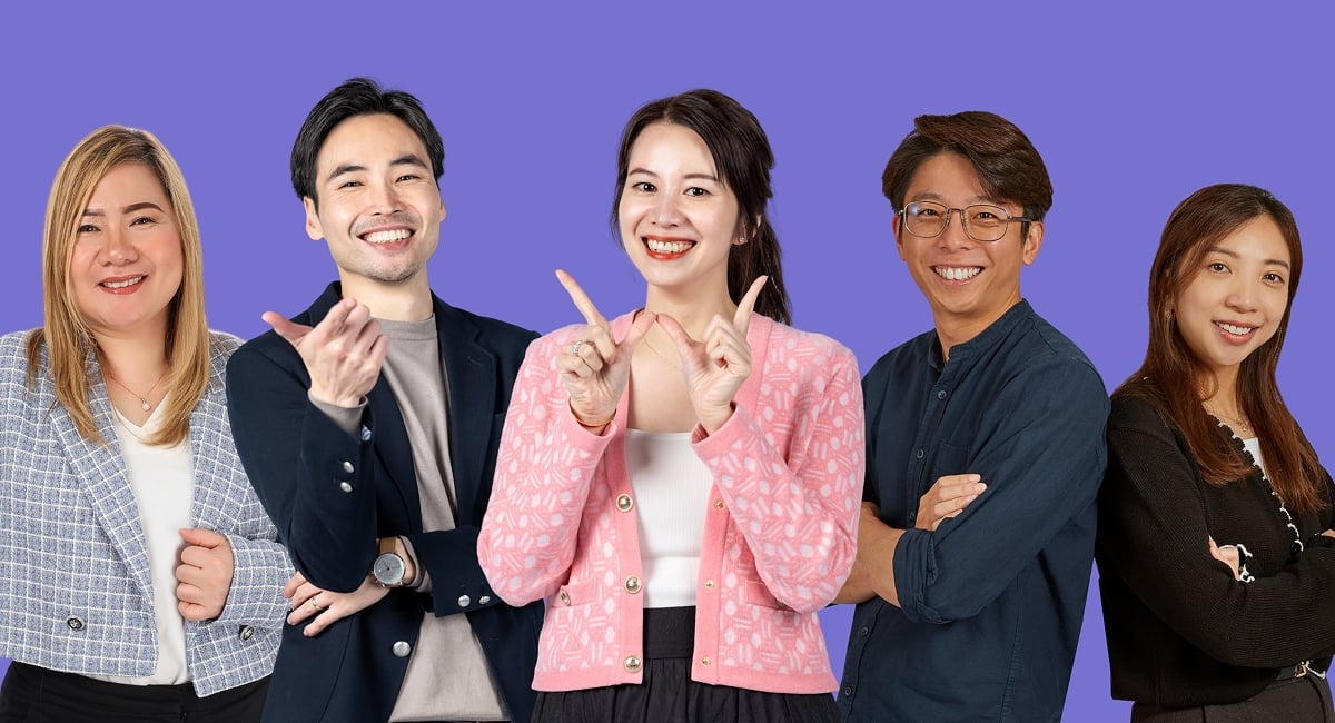 Five people smiling, posing in front of a purple background.
