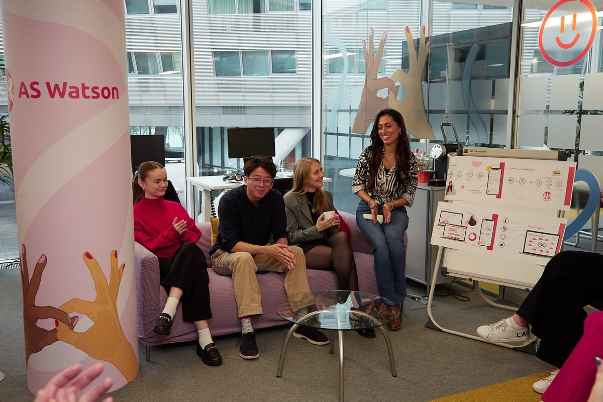 Group of people in an office setting, presentation board.