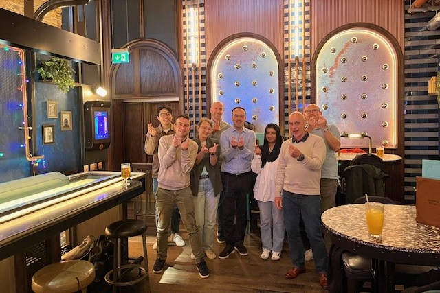 People making heart shapes with their hands in a bar.