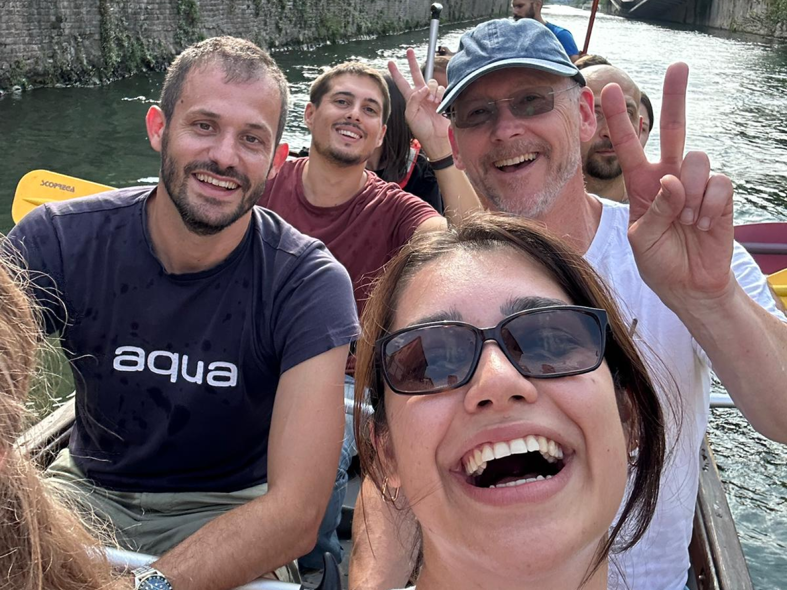 Group of people smiling and making peace signs on a boat.