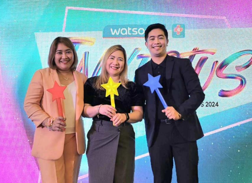 Three people holding star wands at an event.