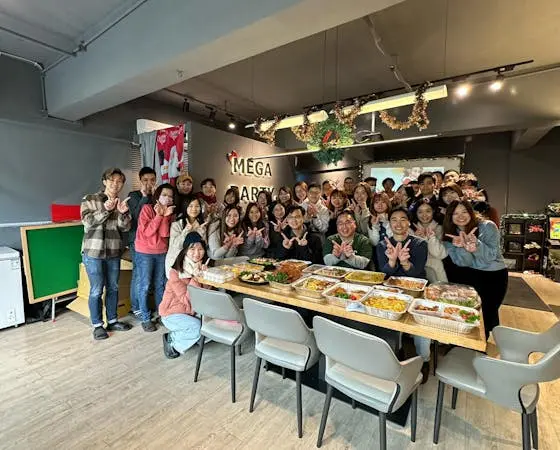 Group of people at a party with food on a table.