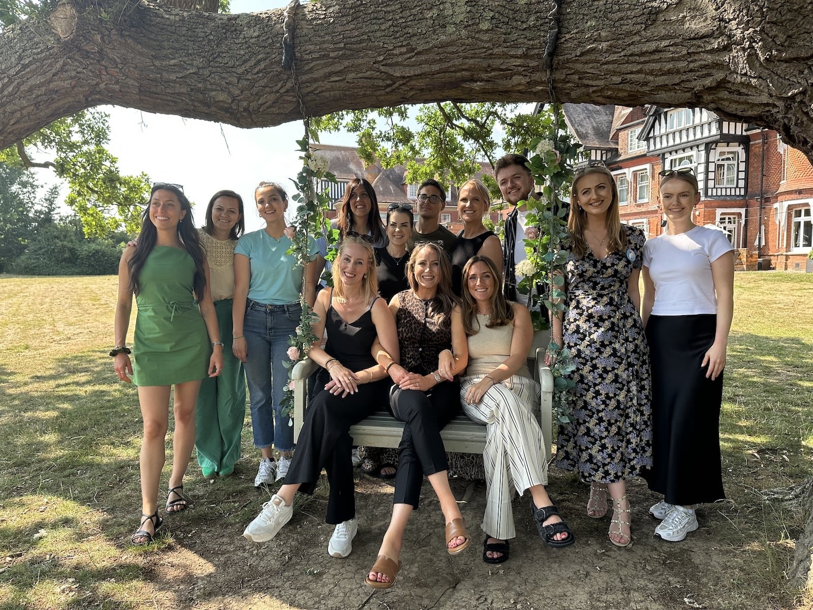 Group of people posing under a tree, smiling.