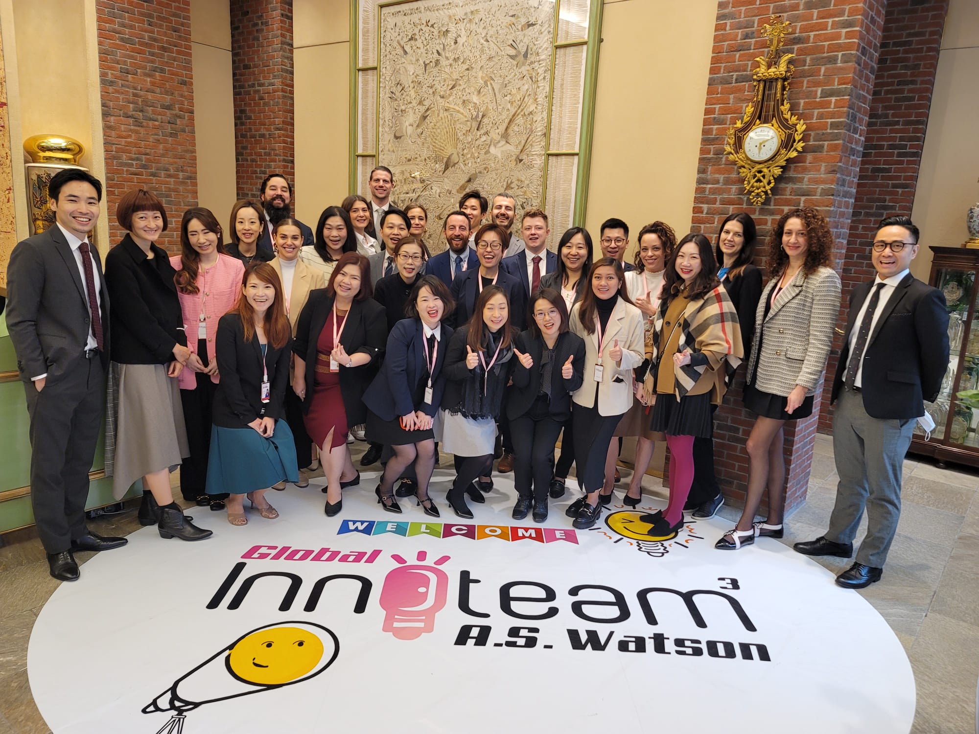 Group of people posing for a photo with a welcome mat.