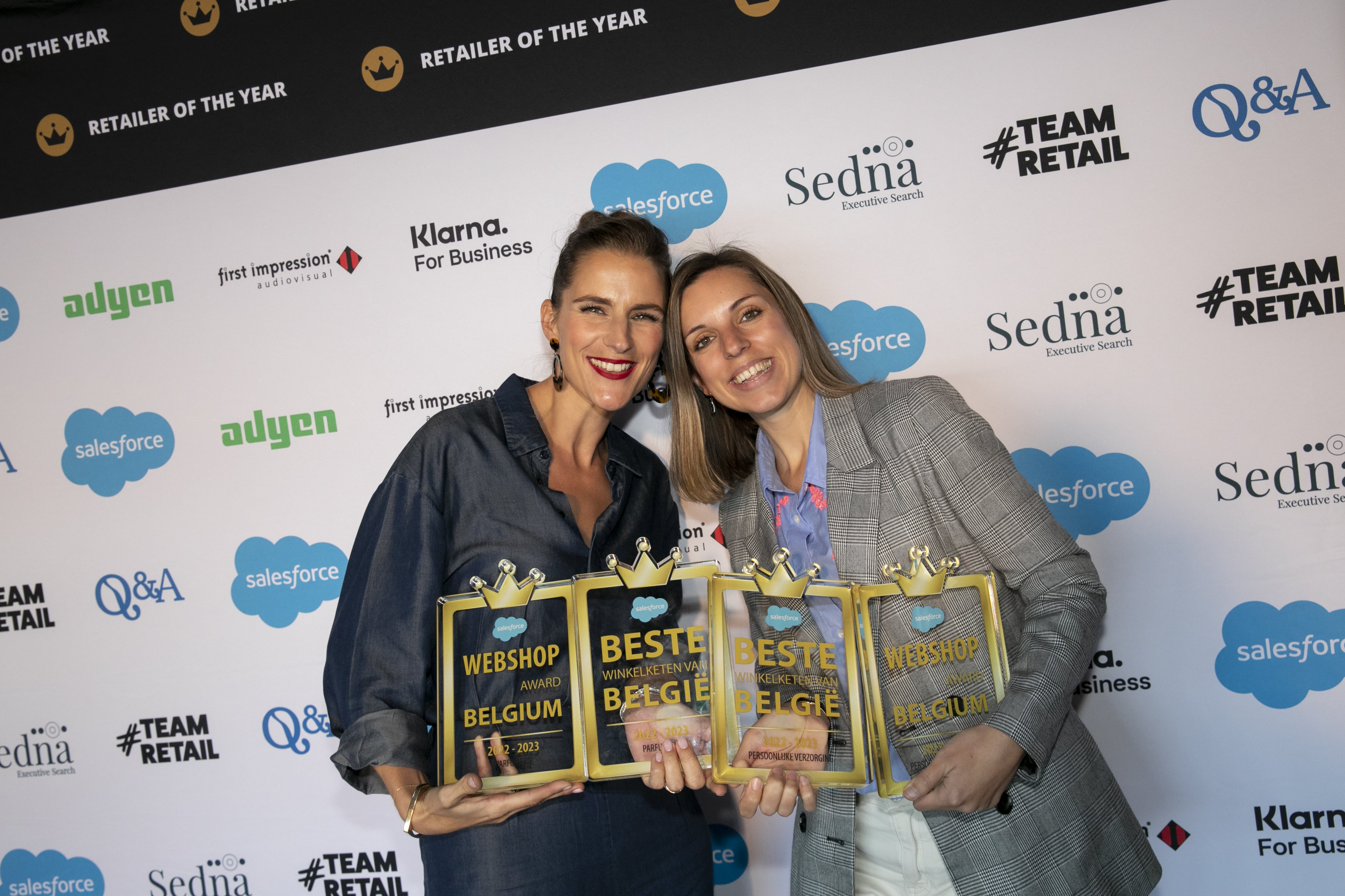 Two women holding awards for Webshop and Best Retailer in Belgium.