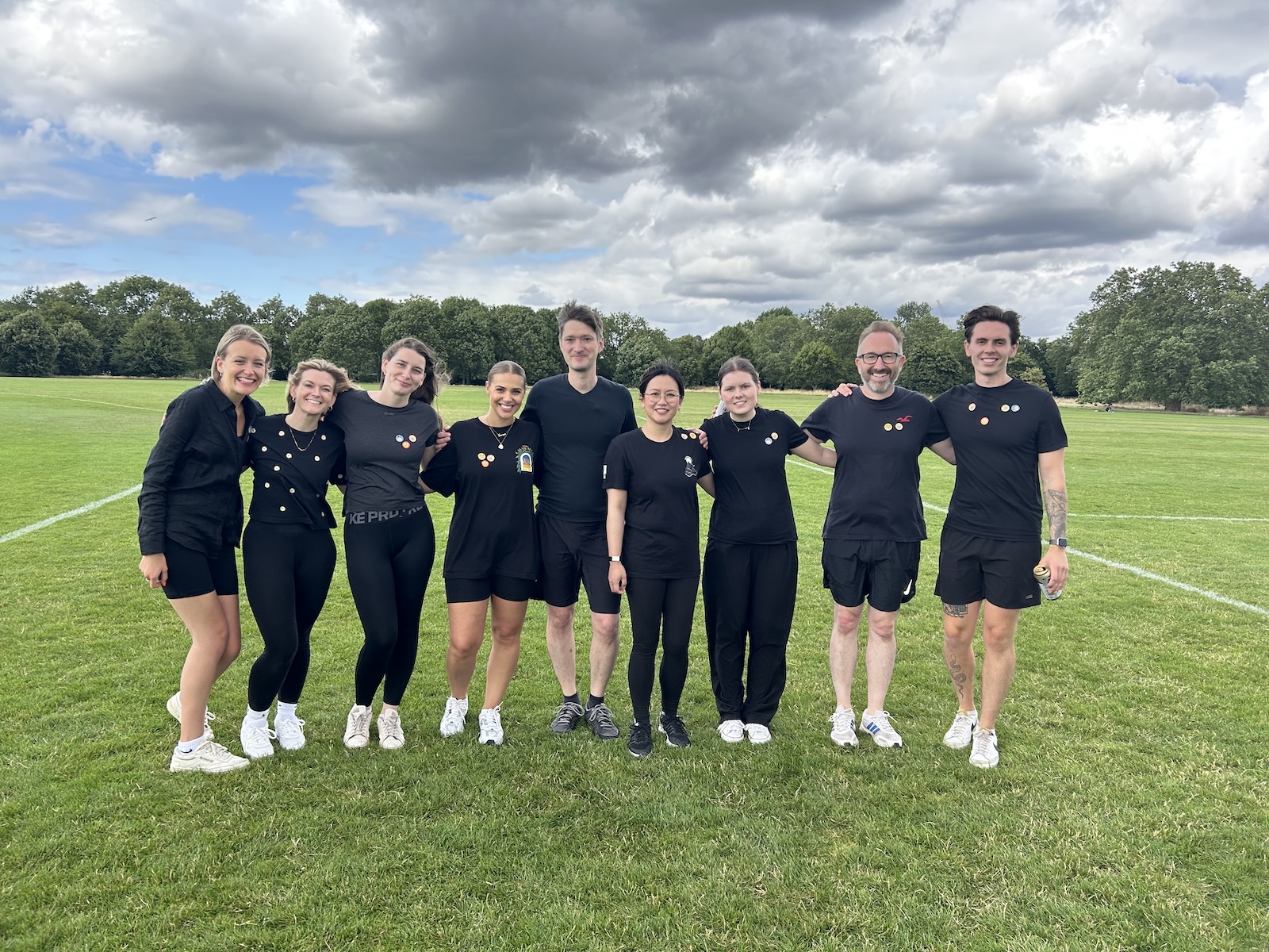 Group of people in black shirts and shorts on a field.