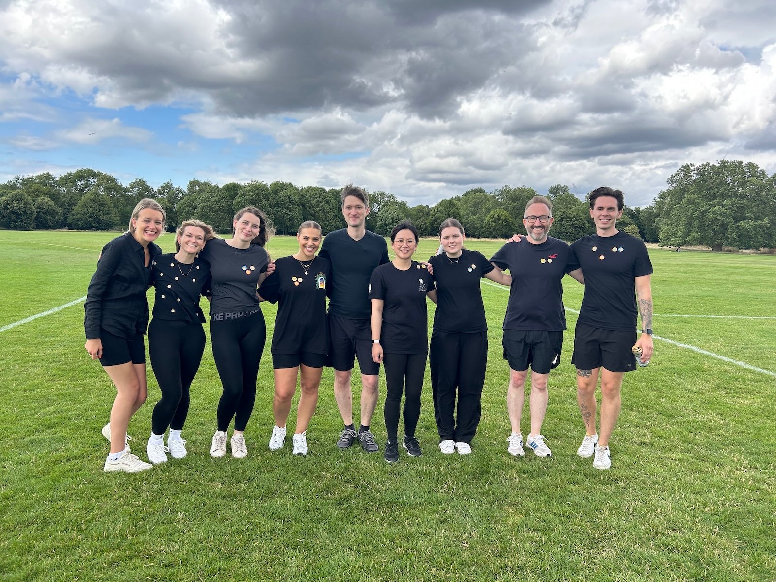 Group of people in black shirts and shorts on a field.