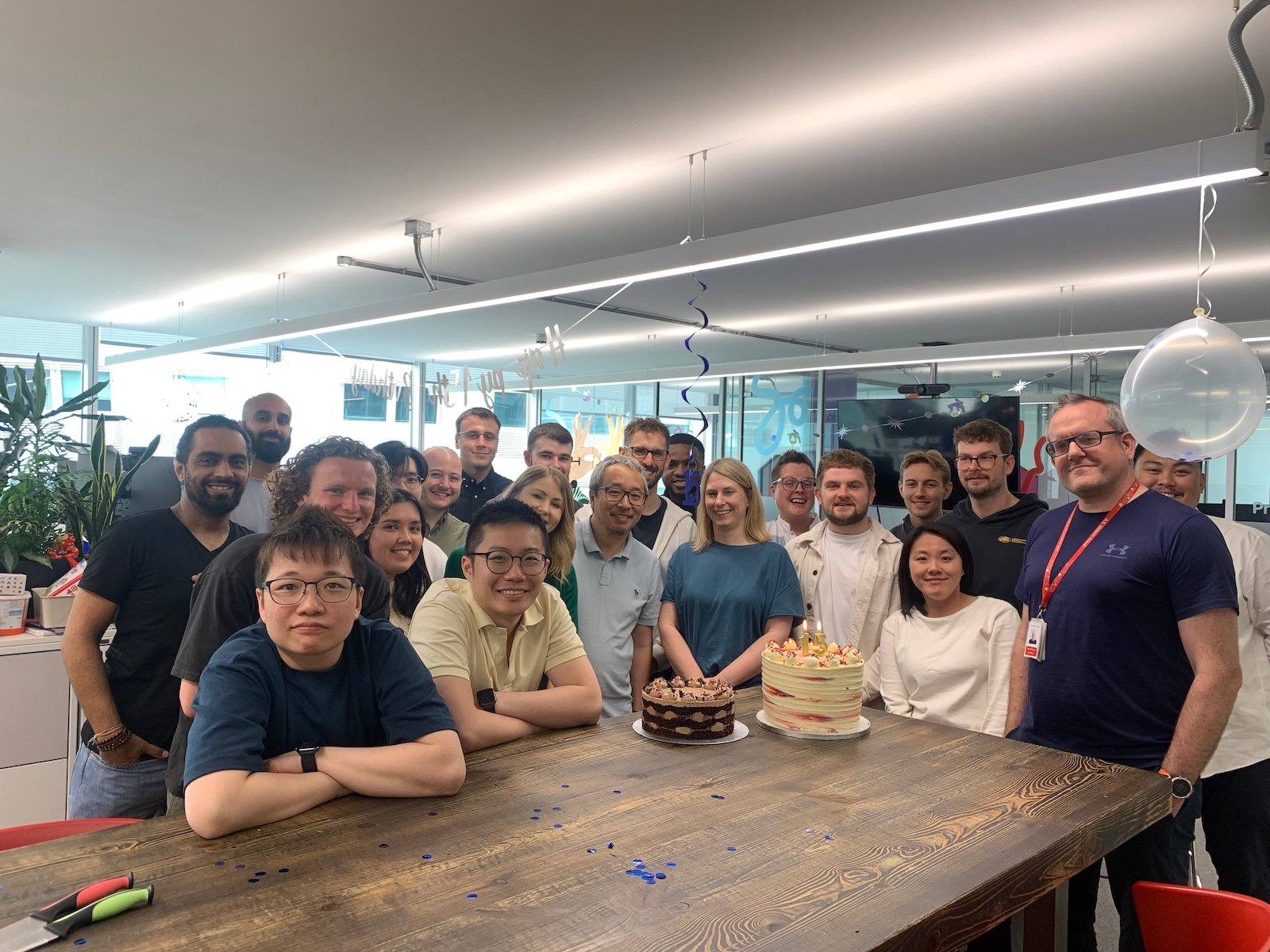 Group of people celebrating with cakes and balloons.