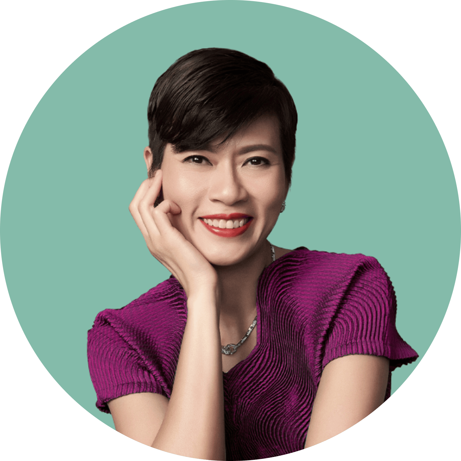 Woman with short hair, smiling, wearing a purple top, and a necklace.