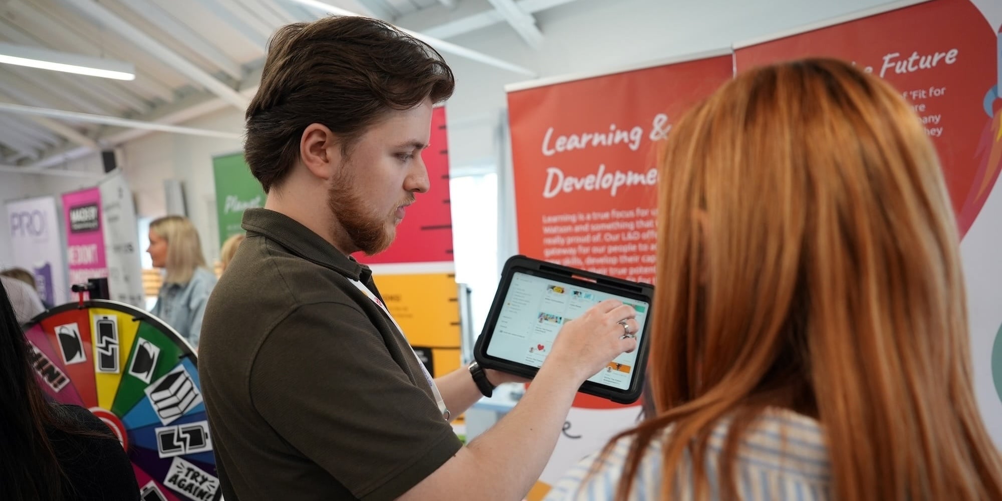 Man showing tablet to a woman at a conference.