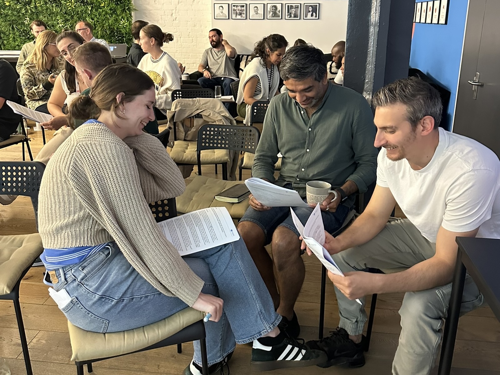 People reading documents, smiling, in a meeting setting.