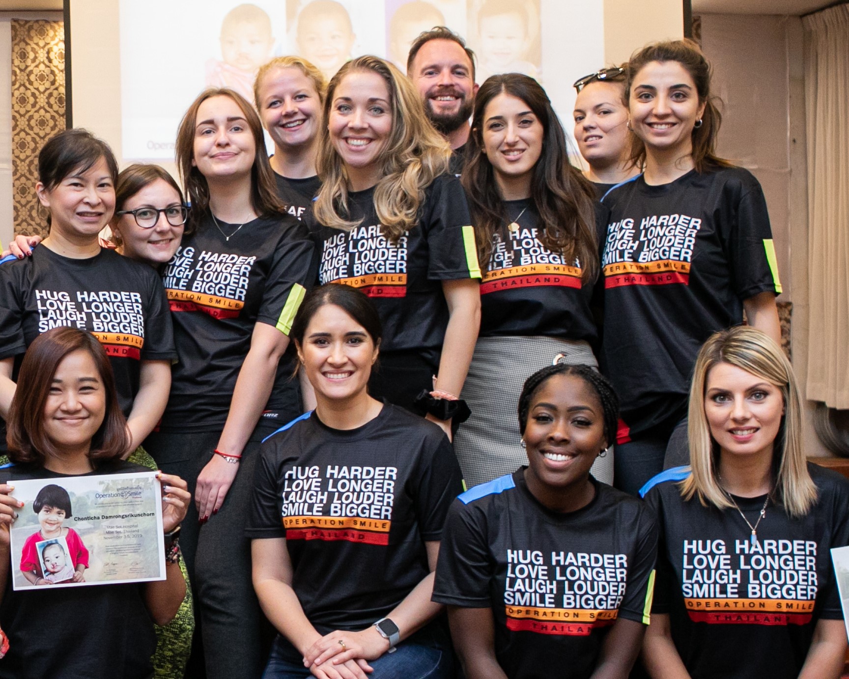Group of people wearing black Operation Smile shirts, smiling.